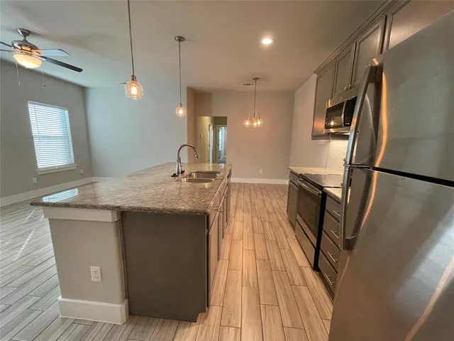 a kitchen with stainless steel appliances granite countertop a sink a refrigerator and a stove