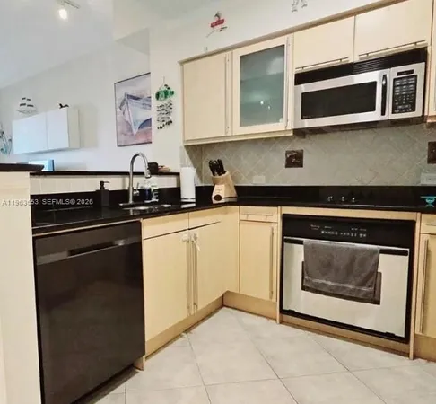 a utility room with stainless steel appliances a refrigerator a sink and cabinets