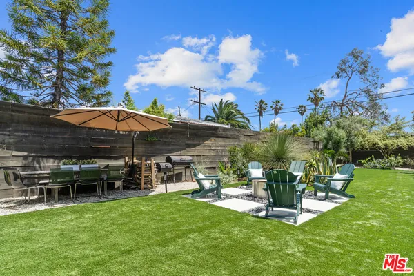 a view of a chair and table in backyard of the house