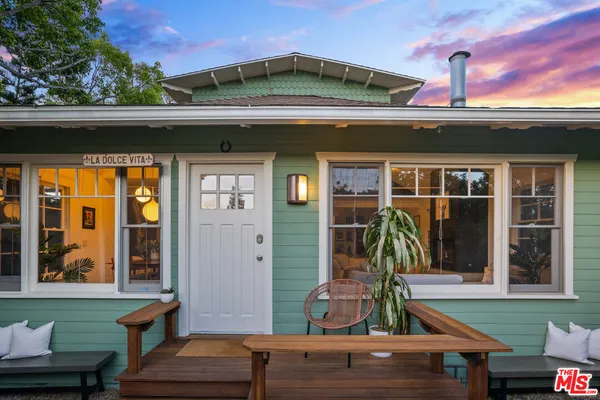 a backyard of a house with table and chairs under an umbrella