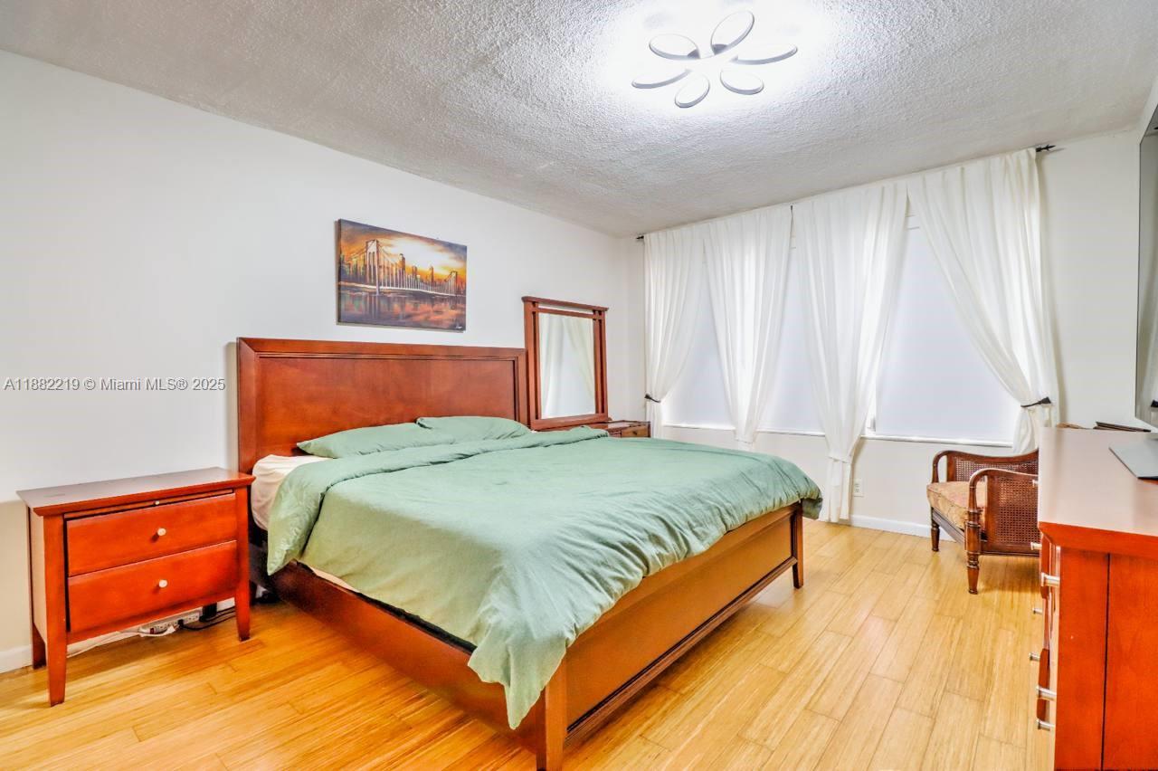 850 Northeast 12th Avenue, Unit 210 Hallandale Beach, FL 33009 - Photo 12 of 16 a bedroom with a bed and wooden floor