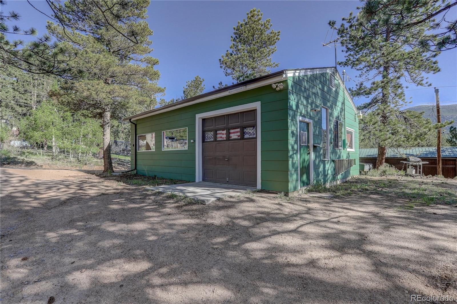 191 Anderson Road Bailey, CO 80421 - Photo 3 of 38 a front view of a house with a yard and garage