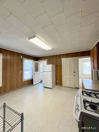 a living room with stainless steel appliances furniture a flat screen tv and kitchen view