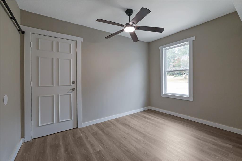 4913 Windsor Downs Drive Decatur, GA 30035 - Photo 23 of 26 an empty room with wooden floor ceiling fan and windows