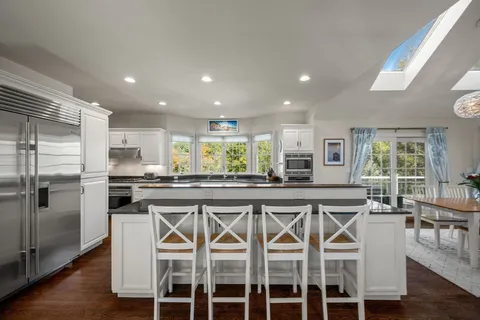 a kitchen with stainless steel appliances granite countertop a table chairs sink and cabinets