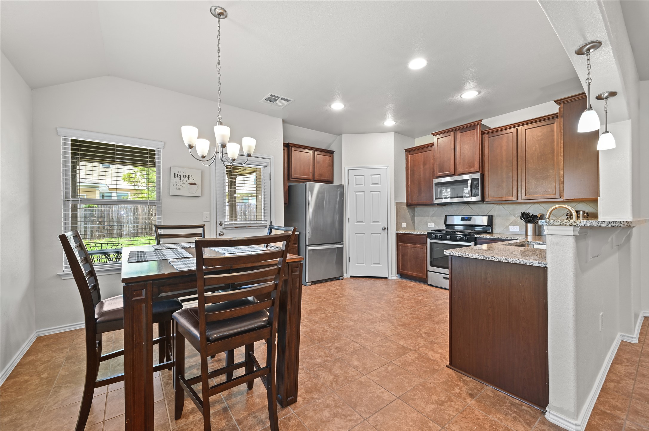 303 Limerick Road Buda, TX 78610 - Photo 5 of 23 Open-concept kitchen and dining area featuring tile flooring, dark wood-finish cabinetry, stainless steel appliances, and granite countertops