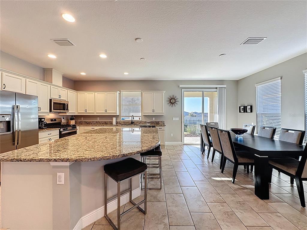 115 Silver Maple Road Groveland, FL 34736 - Photo 17 of 79 a kitchen with stainless steel appliances granite countertop a table chairs refrigerator sink and cabinets