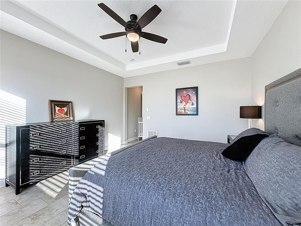 115 Silver Maple Road Groveland, FL 34736 - Photo 32 of 79 a bedroom with a bed and a ceiling fan