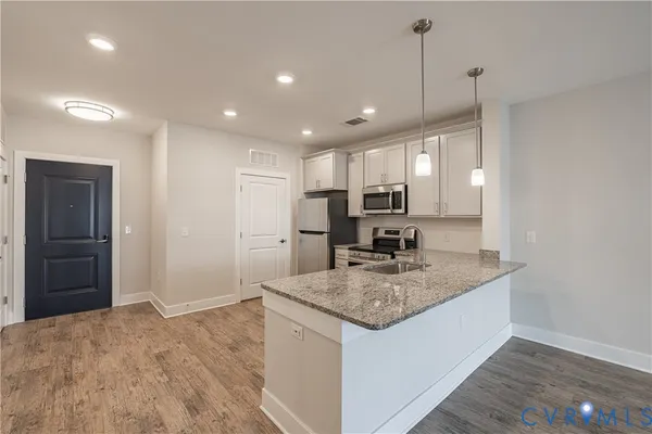 a kitchen with kitchen island granite countertop wooden cabinets a refrigerator and a sink