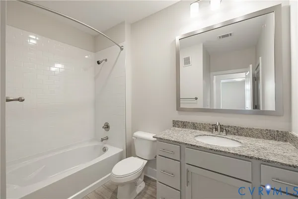 a bathroom with a granite countertop sink toilet mirror and bathtub