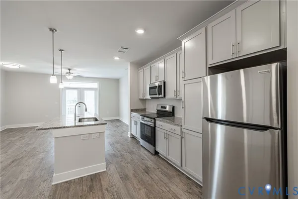 a kitchen with stainless steel appliances granite countertop a refrigerator a stove a sink dishwasher and a refrigerator with wooden floor