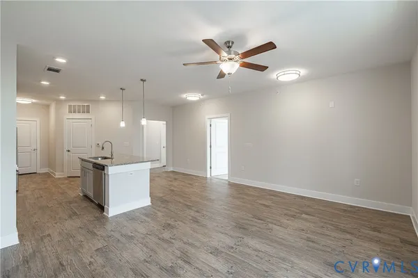 an empty room with wooden floor ceiling fan and windows