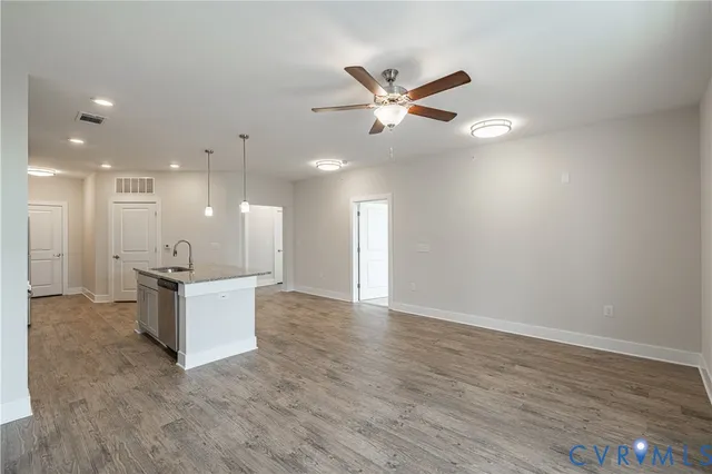 an empty room with wooden floor ceiling fan and windows