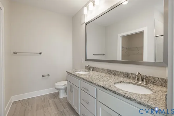 a bathroom with a granite countertop sink a toilet and a mirror