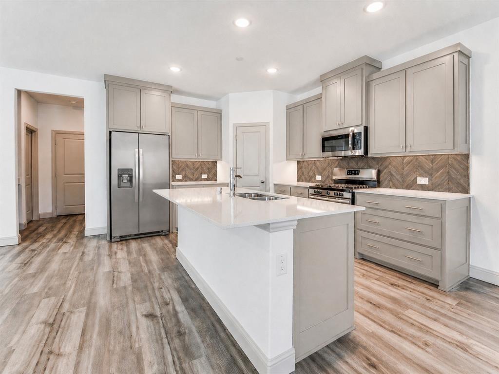 8913 Swallowtail Street Frisco, TX 75035 - Photo 10 of 38 a kitchen with stainless steel appliances a refrigerator stove microwave and sink