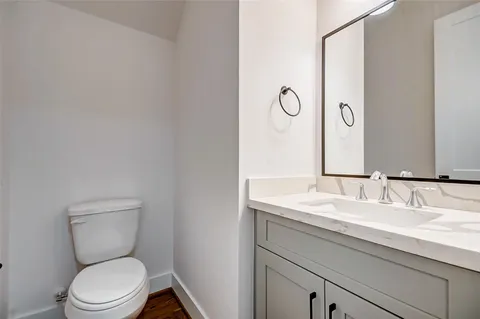 a bathroom with a granite countertop toilet sink and mirror