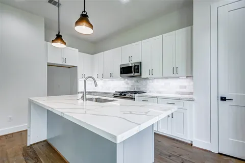 a kitchen with stainless steel appliances granite countertop a stove a sink dishwasher and a microwave with wooden floor