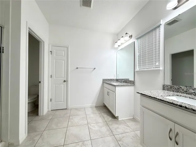 a spacious bathroom with a granite countertop sink a mirror and a bathtub