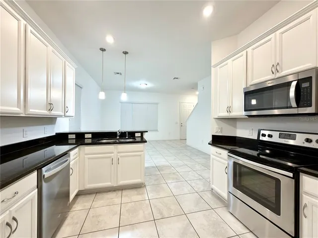 a kitchen with granite countertop a stove a sink and a microwave