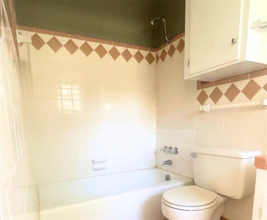 2609 Washington Street Commerce, TX 75428 - Photo 11 of 20 a bathroom with a toilet and a shower curtain