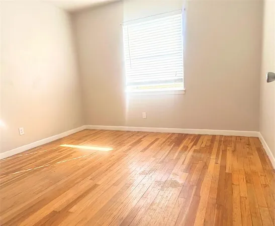 an empty room with wooden floor and a window