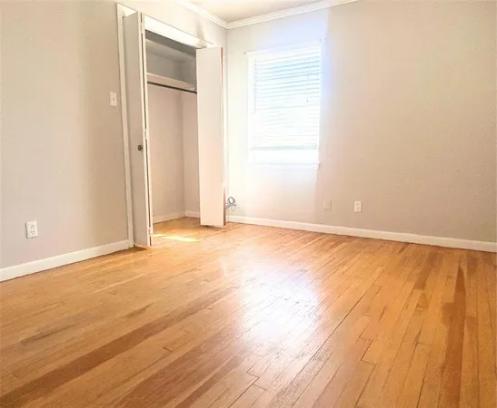 an empty room with wooden floor and windows with curtains