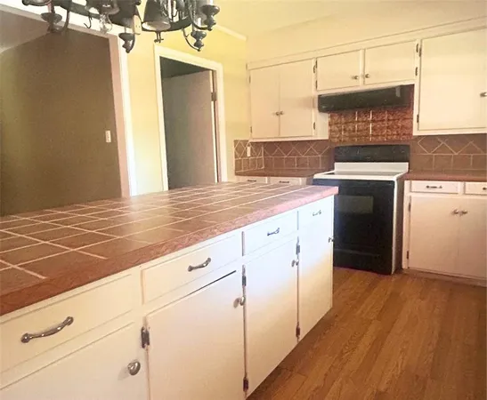 a kitchen with stainless steel appliances granite countertop a stove a sink and white cabinets