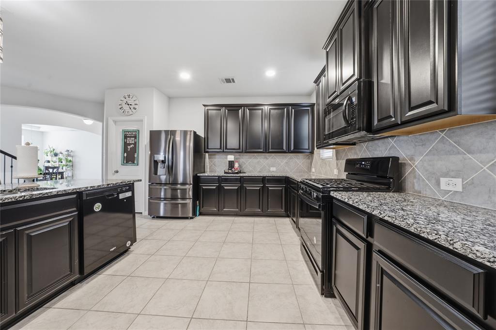 4542 Kipling Avenue Aubrey, TX 76227 - Photo 8 of 34 a large kitchen with stainless steel appliances granite countertop a stove top oven a sink and dishwasher