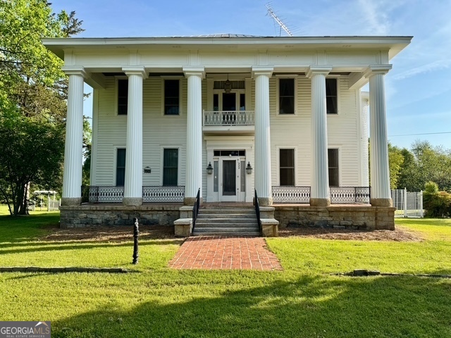 a house that has a big yard with swimming pool in front of it