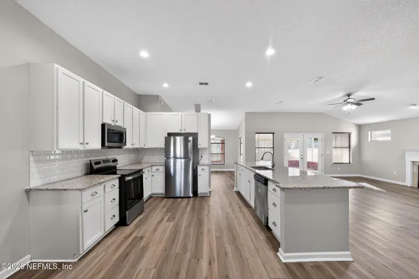 a kitchen with stainless steel appliances granite countertop refrigerator a sink dishwasher a stove top oven a refrigerator with wooden floor
