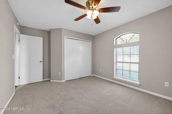 an empty room with windows and fan