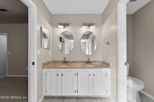 a bathroom with a granite countertop double vanity sinks and a mirror