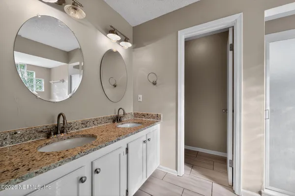a bathroom with a granite countertop double vanity sinks and a mirror