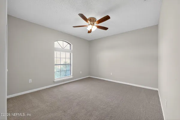 an empty room with windows and fan
