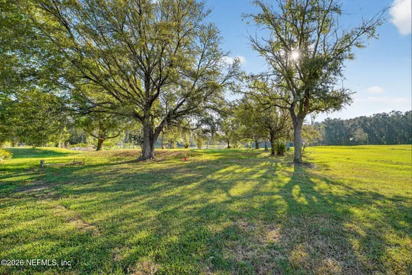 a view of a house with a big yard and large trees