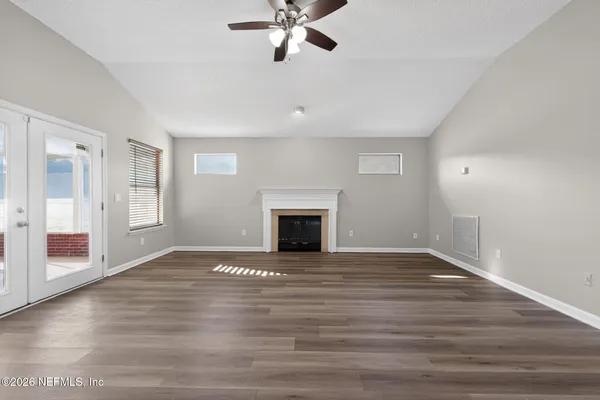 a view of an empty room with wooden floor fireplace and a window