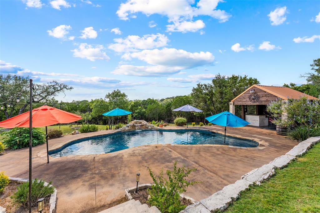 124 Bluffview Circle China Spring, TX 76633 - Photo 31 of 40 Freeform swimming pool with rock waterfall feature, expansive deck, and a stone and wood-clad outdoor bar structure