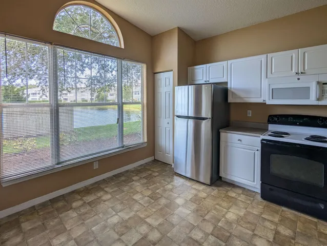 a kitchen with a refrigerator a stove top oven and a large window