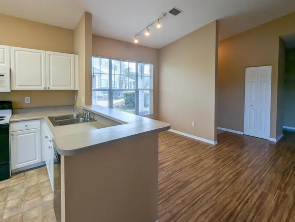 a kitchen with a sink a stove cabinets and wooden floor