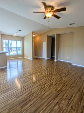 a view of an empty room with window and wooden floor