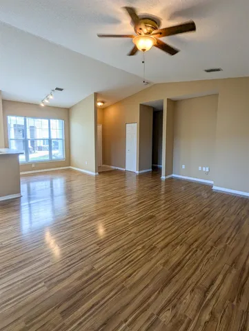 a view of an empty room with window and wooden floor