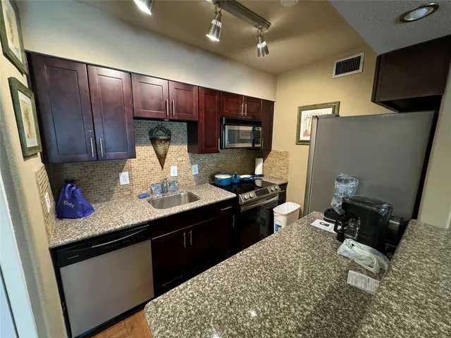 a kitchen with stainless steel appliances kitchen island granite countertop a refrigerator stove and sink
