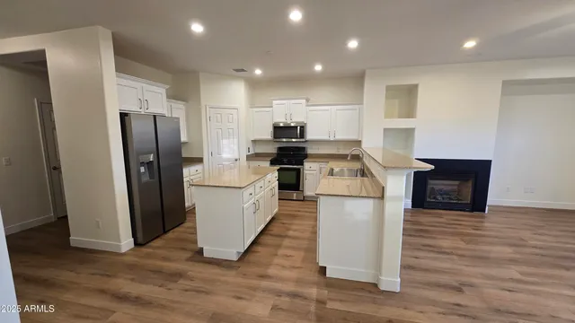 a kitchen with refrigerator and wooden floor