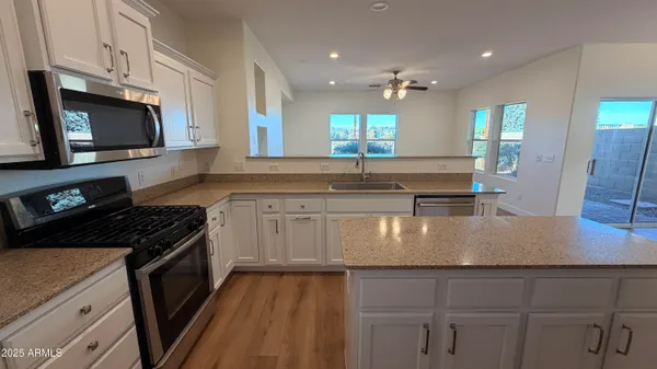 a kitchen with kitchen island granite countertop a sink stainless steel appliances and white cabinets