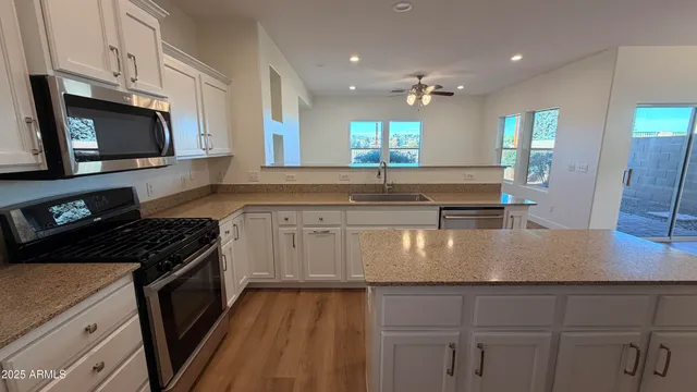 a kitchen with kitchen island granite countertop a sink stainless steel appliances and white cabinets