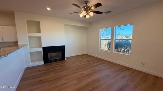 a view of an empty room with a window and wooden floor