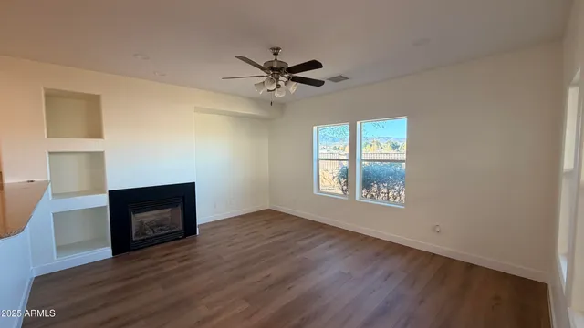 a view of an empty room with a window and wooden floor