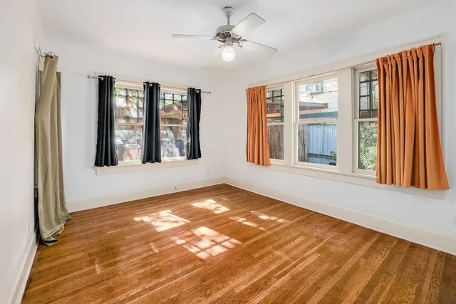 a view of an empty room with a window and wooden floor