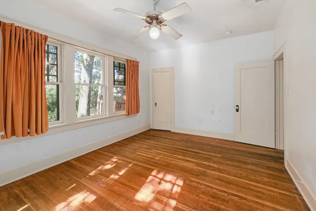 a view of an empty room with window and a chandelier fan