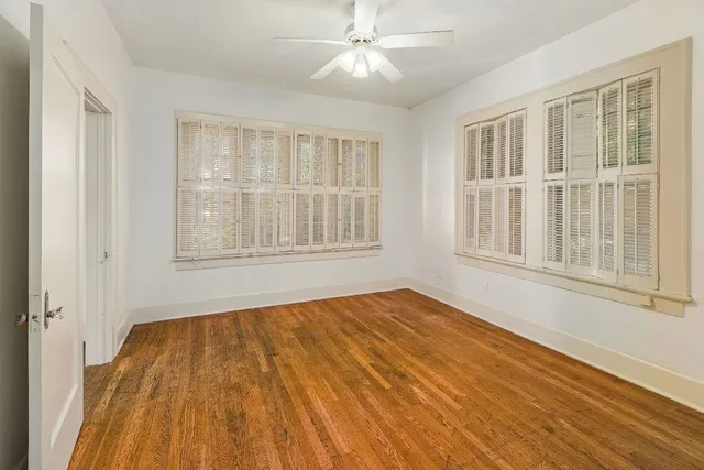 a view of an empty room with wooden floor and windows